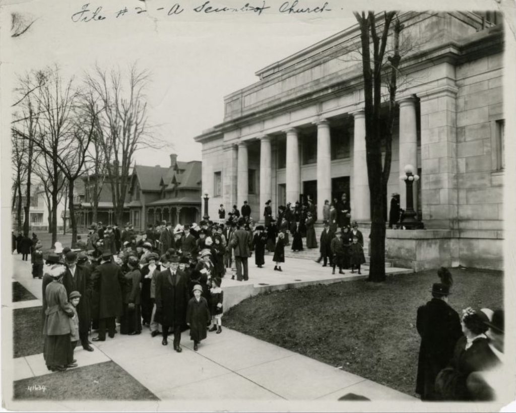 A large group of people leave a church. 