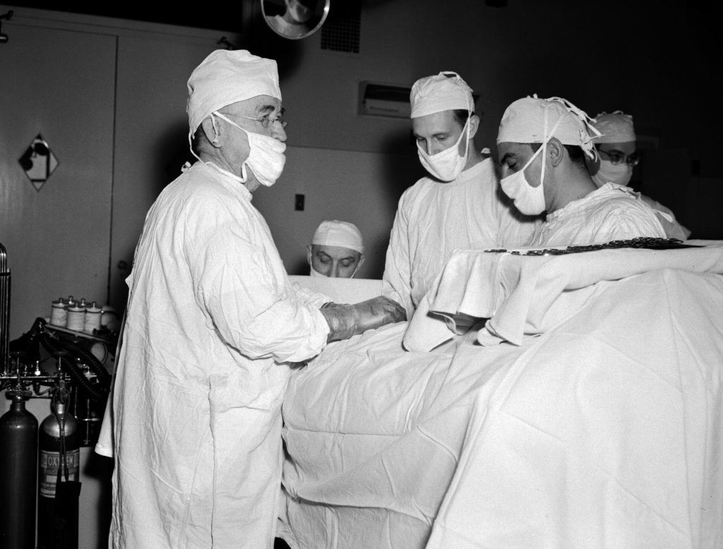 A group of men wearing white surgical gowns and masks perform an operation at St. Vincent's Hospital in Indianapolis.
