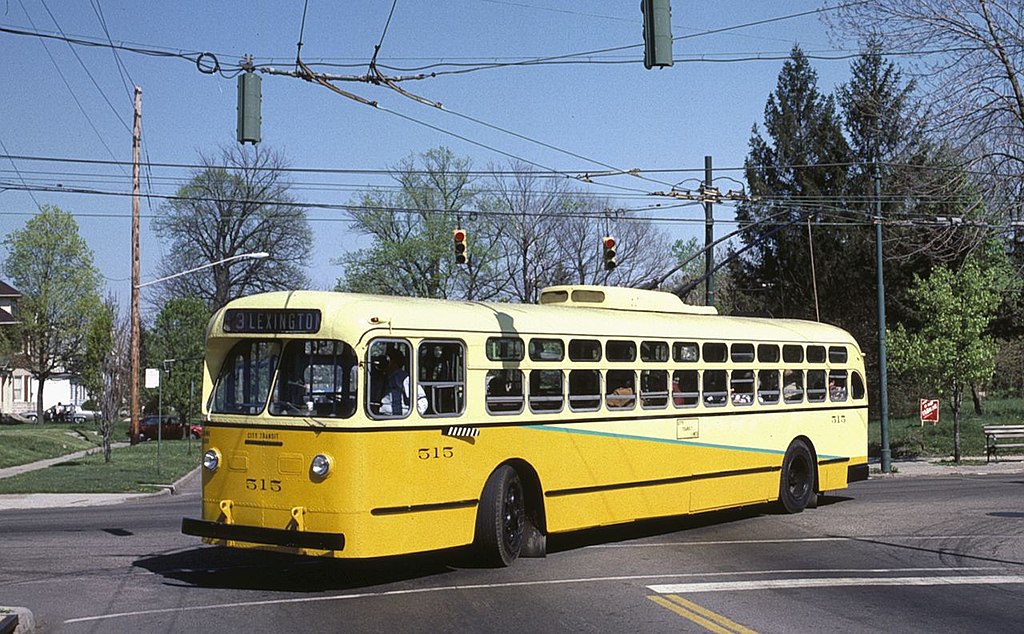 A yellow and white bus is turning in the middle of an intersection. 