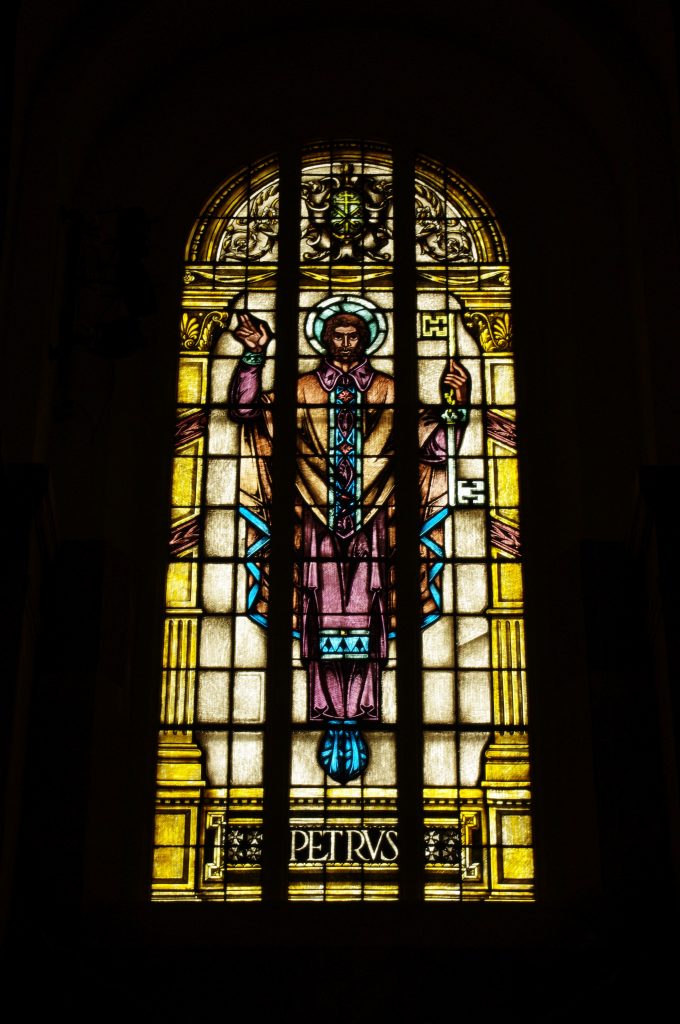 Stained glass window with an arched top. The glass depicts a man with a halo around his head.