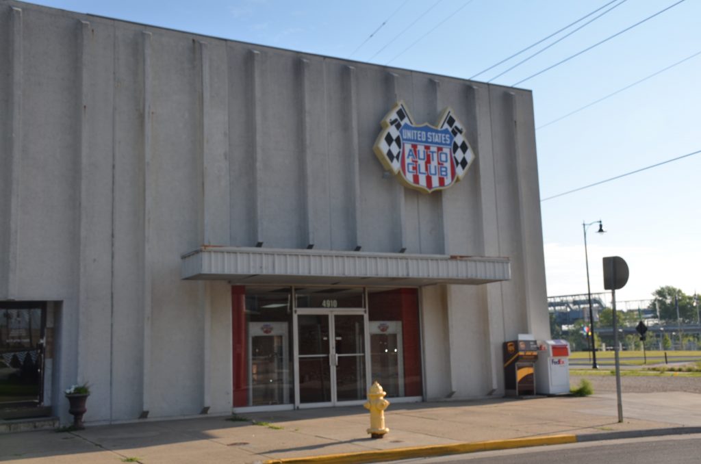 Exterior view of an office building with a large sign with checkered flags that reads "United States Auto Club."