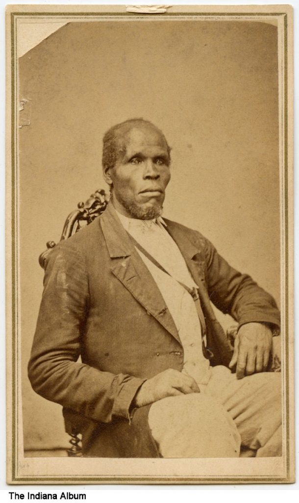 An African American man sits in a chair. 