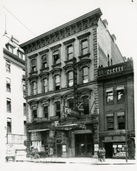 The Italianate-style, four-story building facade features a large marquee sign over the entrance.
