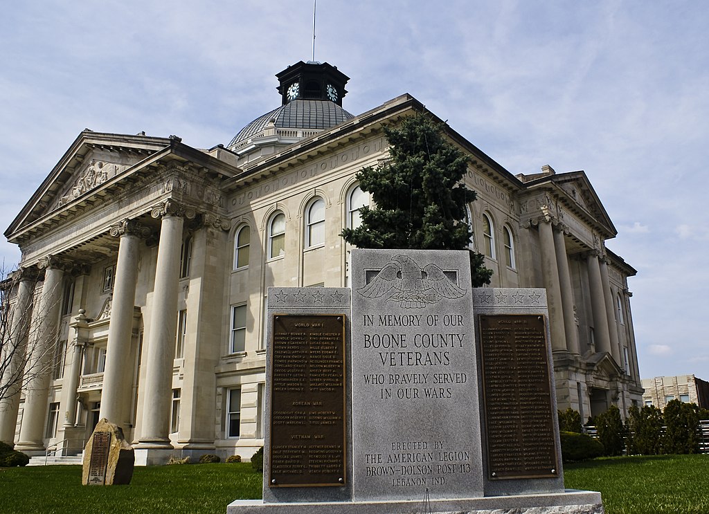 A granite memorial is in the foreground. A greek style courthouse is in the background. 