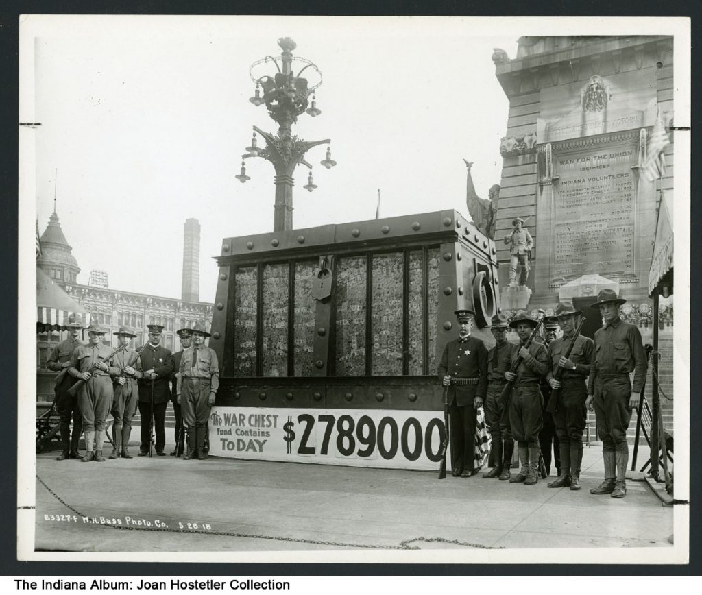 Soldiers stand around a large replica of an iron-bound chest. At the bottom of the chest is a sign reading "The War Chest Fund Contains Today $2,780,000."