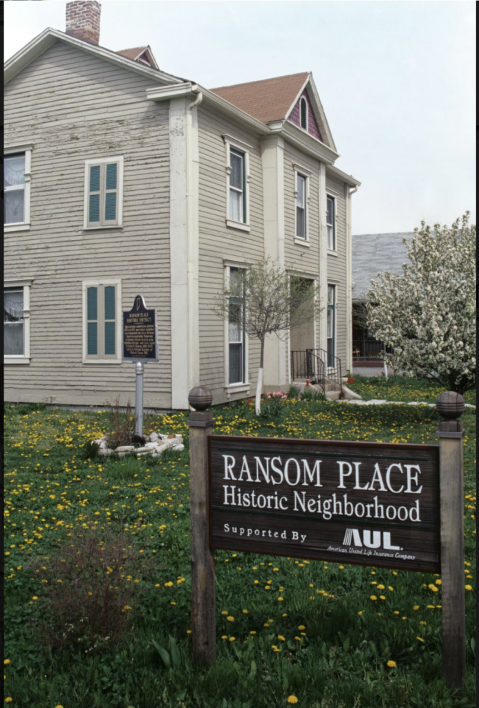 A two-story building with a sign in front that says Ransom Place Historic Neighborhood.