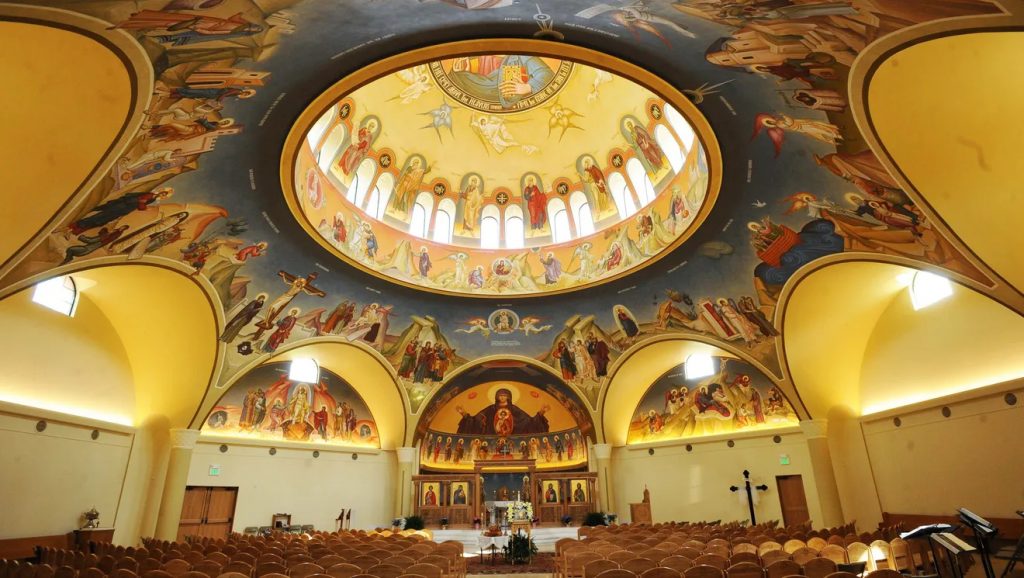Interior of a large church featuring a domed ceiling painted with religious scenes.