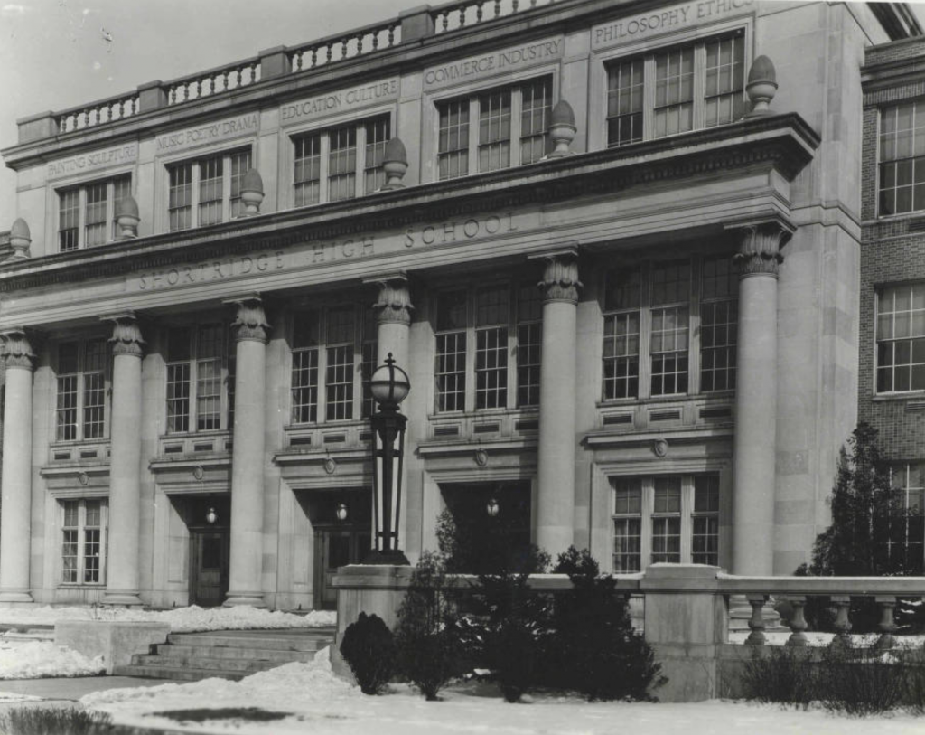 The exterior view of the entrance to the school. The multi-story building is the classical revival style.