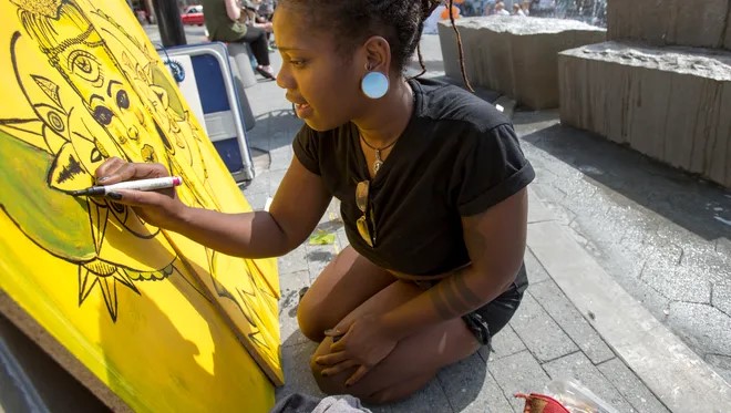 An artist uses a paint pen while working on a large canvas.