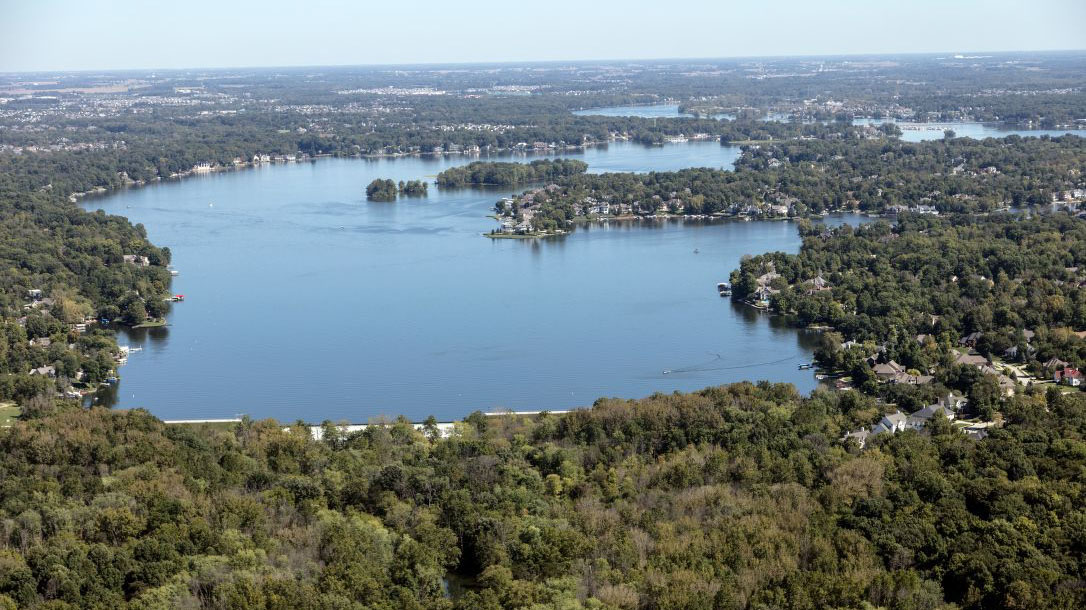 Aerial view of a reservoir surrounded by dense three coverage.
