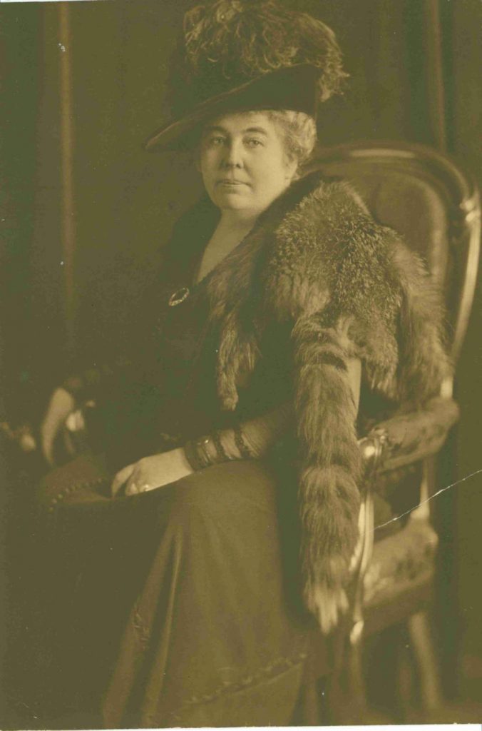 Portrait of Mary Stewart Carey sitting in a chair. She is wearing a fur shawl and a fancy hat with feathers.