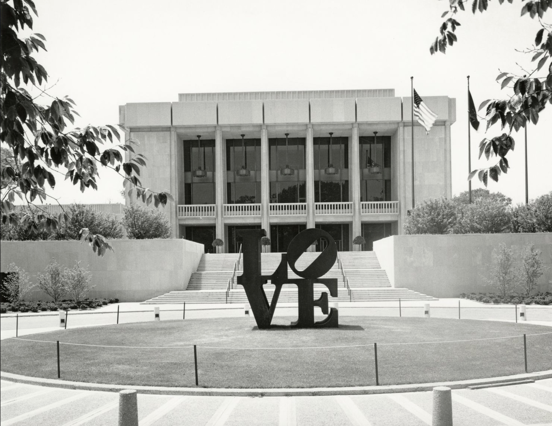 Front entrance of the Indianapolis Museum of Art. A statue that says "LOVE" sits in the middle of a circle of grass in front of the steps that lead up to the museum.