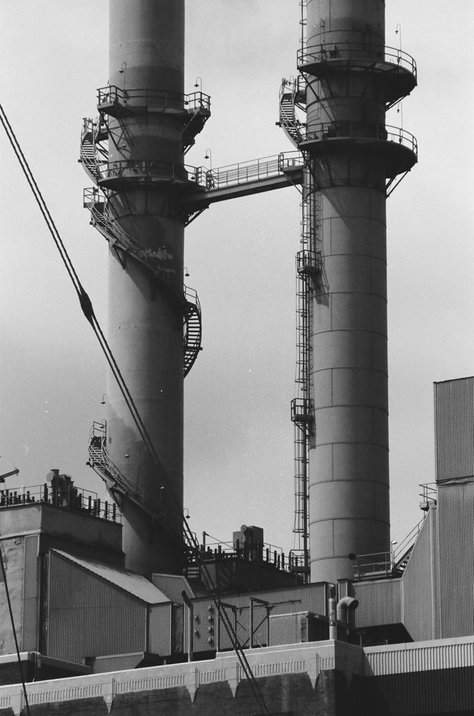 Black and white photo of a pair of smoke stacks.