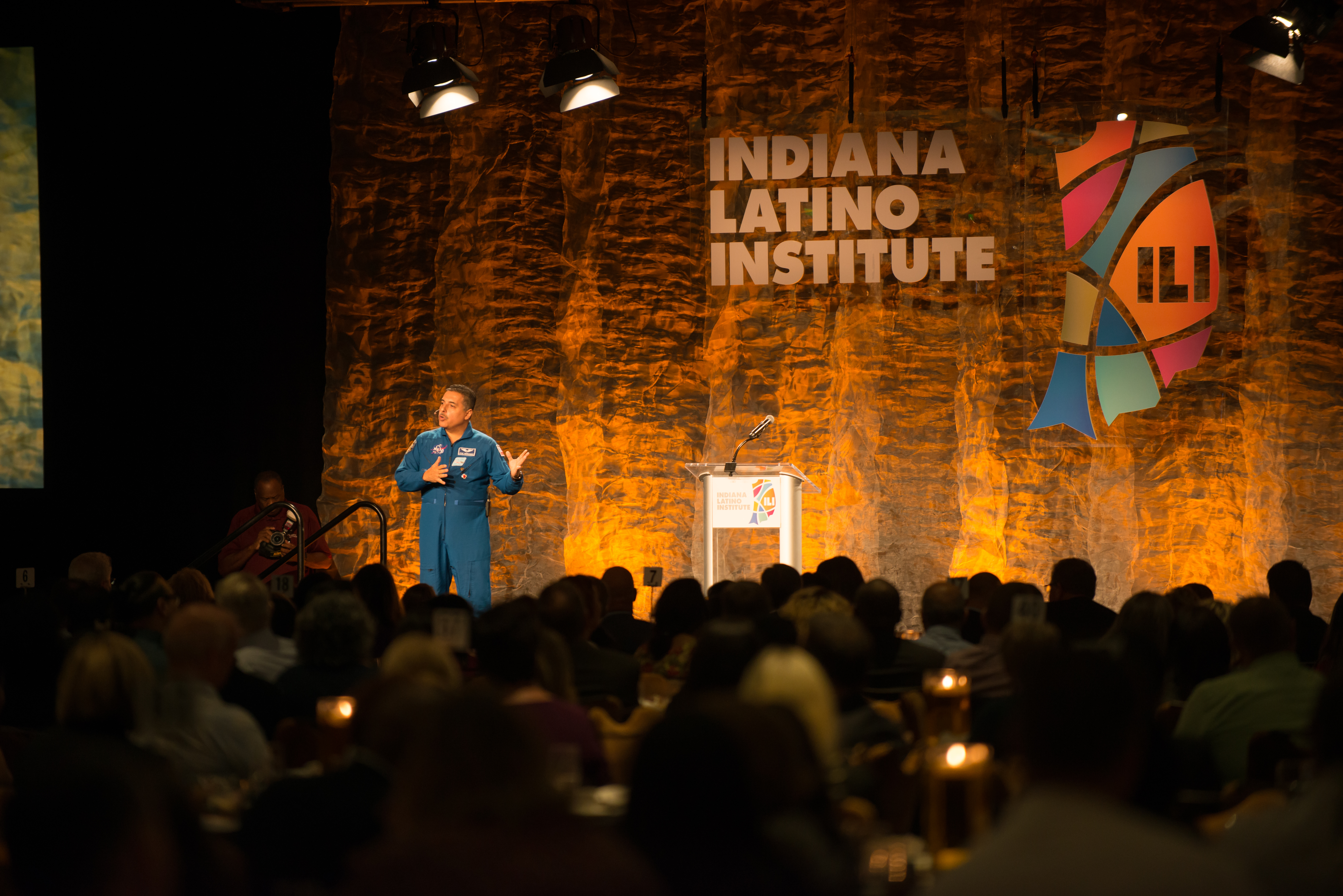 A person stands on a stage in front of an audience. 