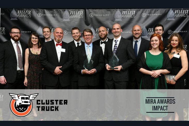 A group of people in formal wear stand together for a posed photograph. A banner across the bottom shows the Cluster Truck logo.