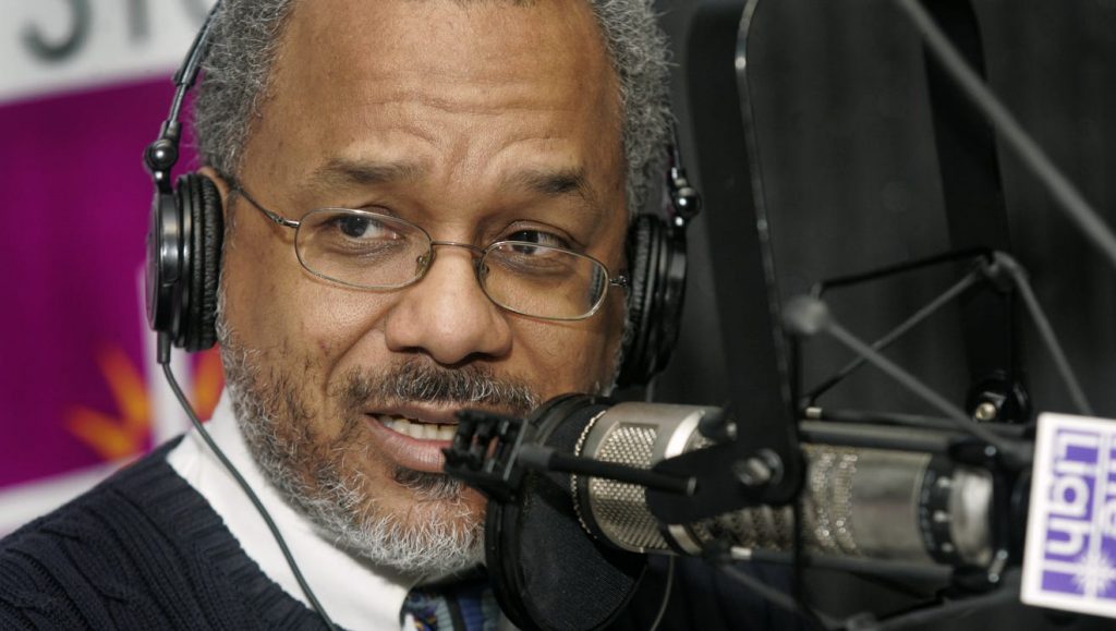 Amos Brown is wearing headphones and speaking into a microphone.
