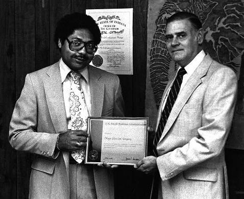 Two men are standing next to each other, both holding one side of a certificate. 