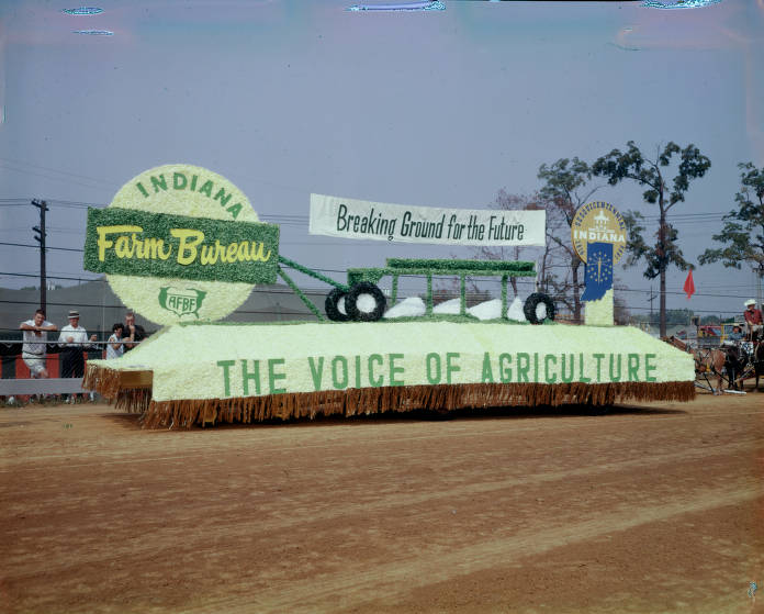 The float has a banner above reading "Breaking Ground for the Future", and the side of the float says "The Voice of Agriculture".