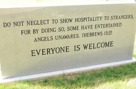 A concrete sign with "Everyone is Welcome" etched into it. 