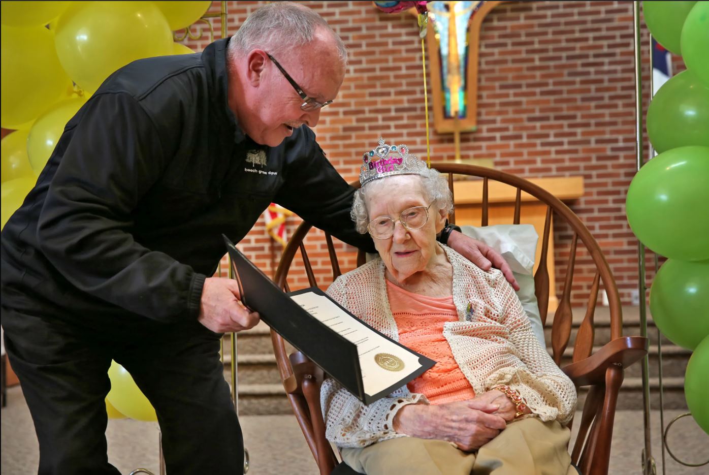 A man shows a certificate to an elderly woman. 