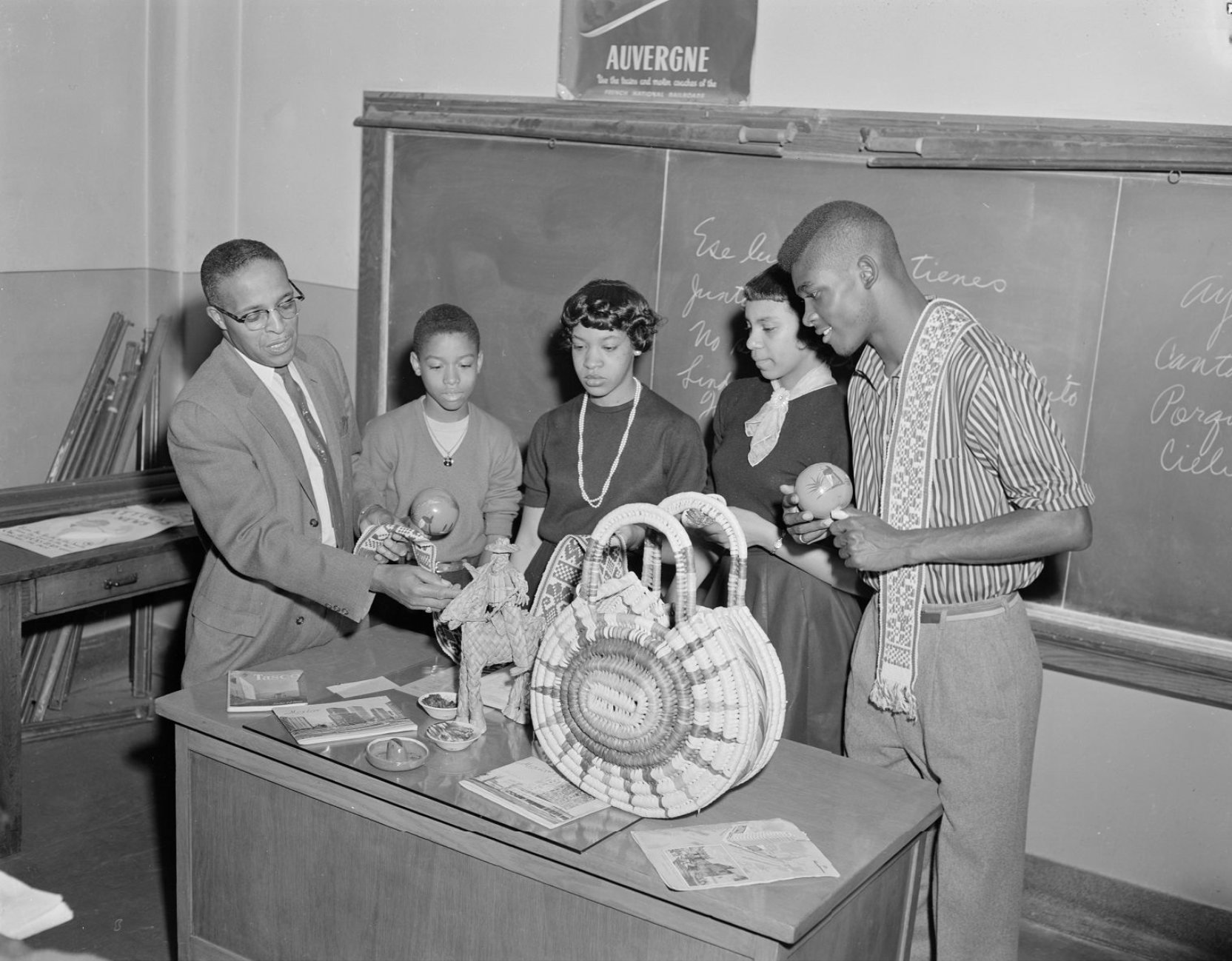 Four students gather around artifacts on a desk. Andrew Ramsey is pointing at one of the artifacts.