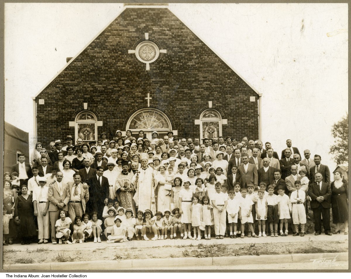 A large group of people poses in front of a brick church.