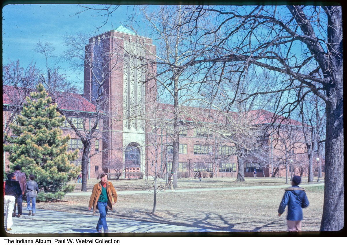 Students walk on the lawn in front of a building. 