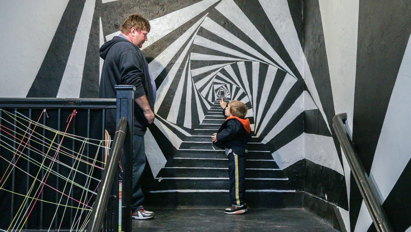An adult and small child look at a wall mural.