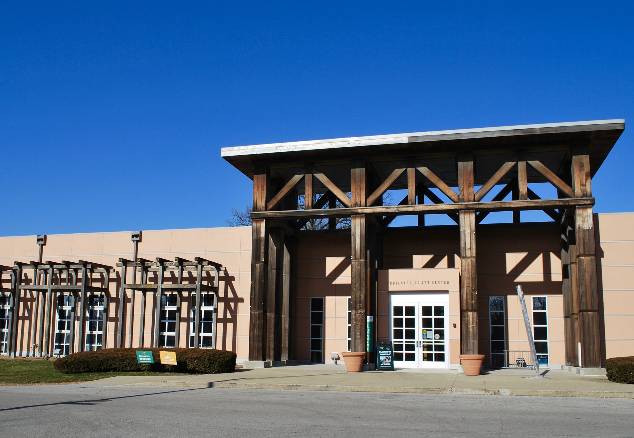 A stucco building entry with large portico columns and large rectangular windows.