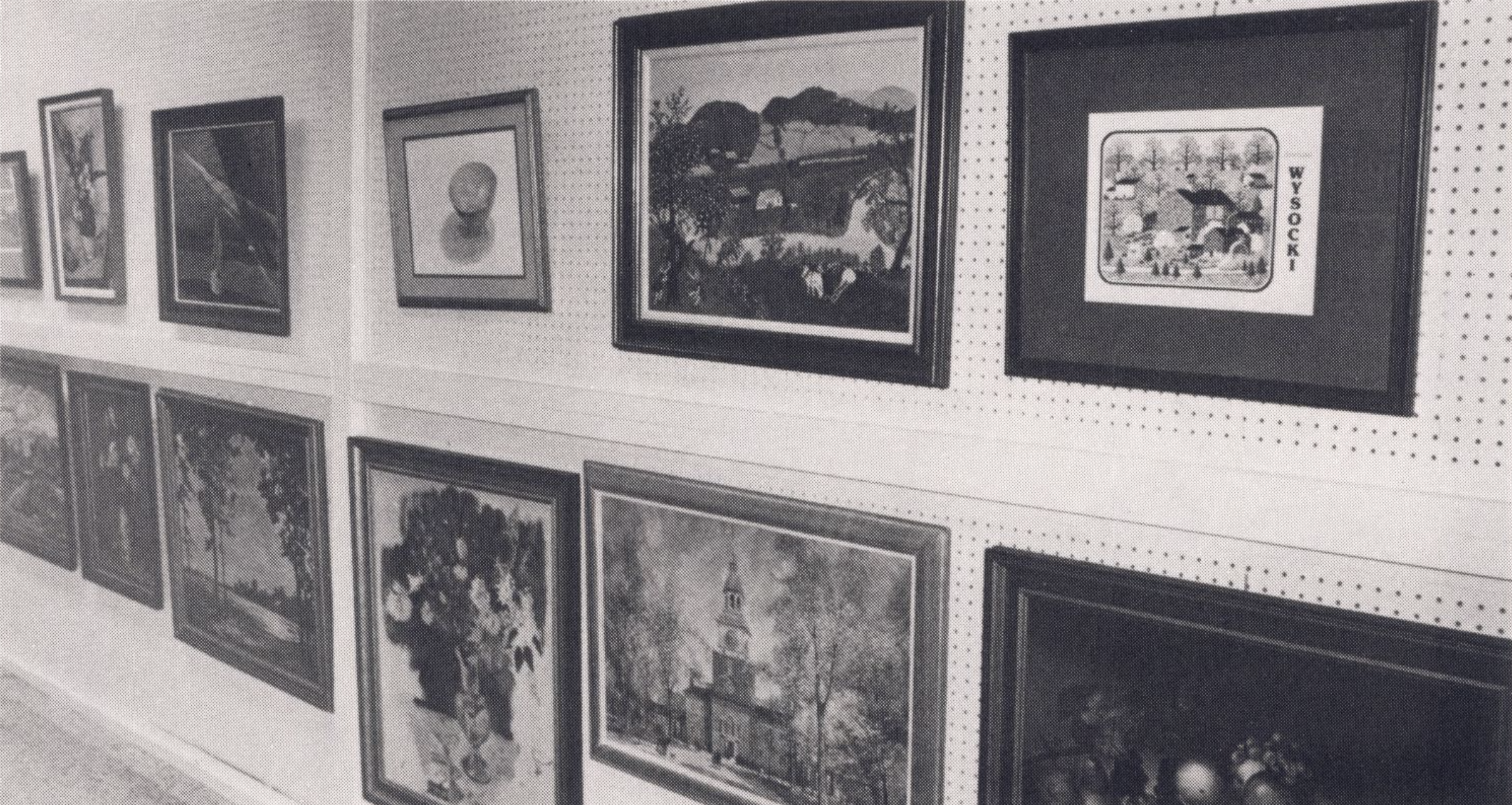 A series of framed art works hang on a wall.