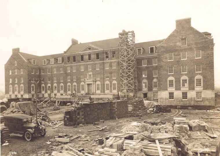 Construction materials fill the lawn in front of a partially constructed building.