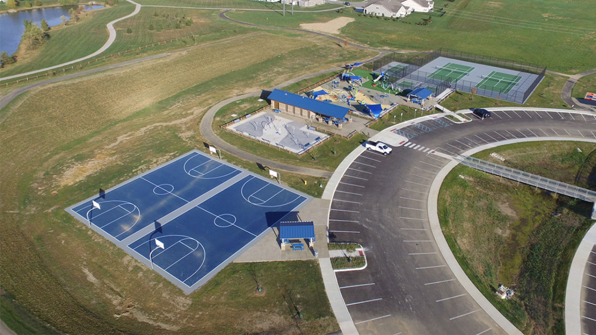 An overhead view showing basketball and tennis courts, a splash pad, and a playground. 