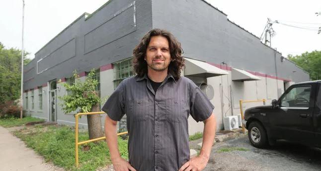 A man stands in front of a building.