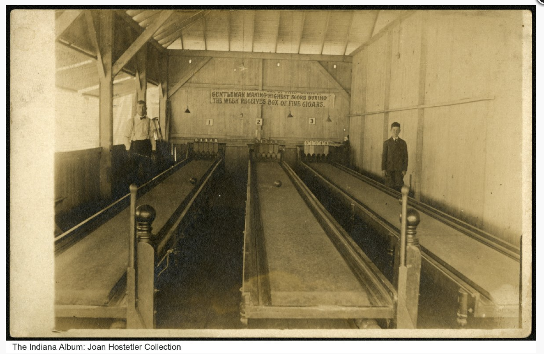 Three raised bowling lanes. Two men stand at the end of the lanes.