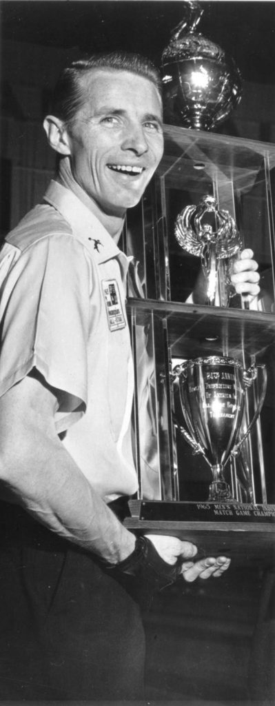A man stands holding a large three-tiered trophy.