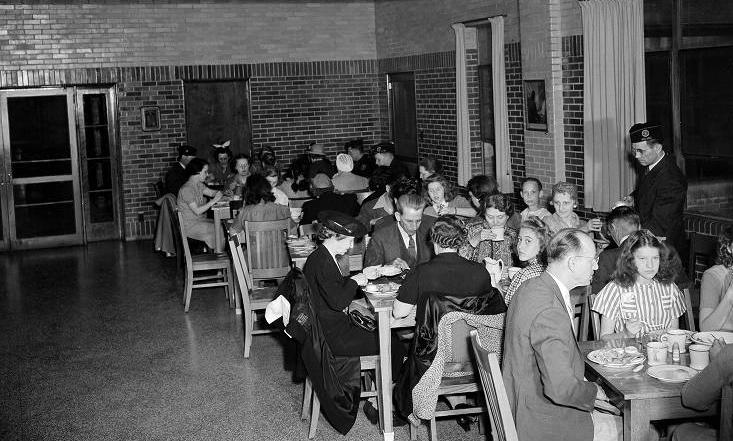 Several people sit at tables eating in a room.