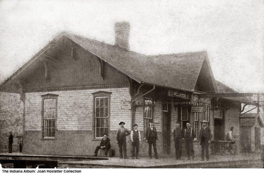 Several men stand in front of a depot building.