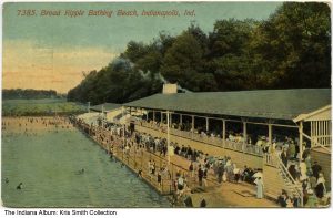 A postcard reads "7385. Broad Ripple Bathing Beach, Indianapolis, Ind." It is a rendering of a large pool with a wide walkway and covered observation stands running the length of the pool.
