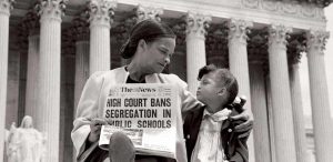Mrs. Nettie Hunt, sitting on the steps of the Supreme Court, holding newspaper, explaining to her daughter Nikie the meaning of the Supreme Court's decision banning school segregation, 1954