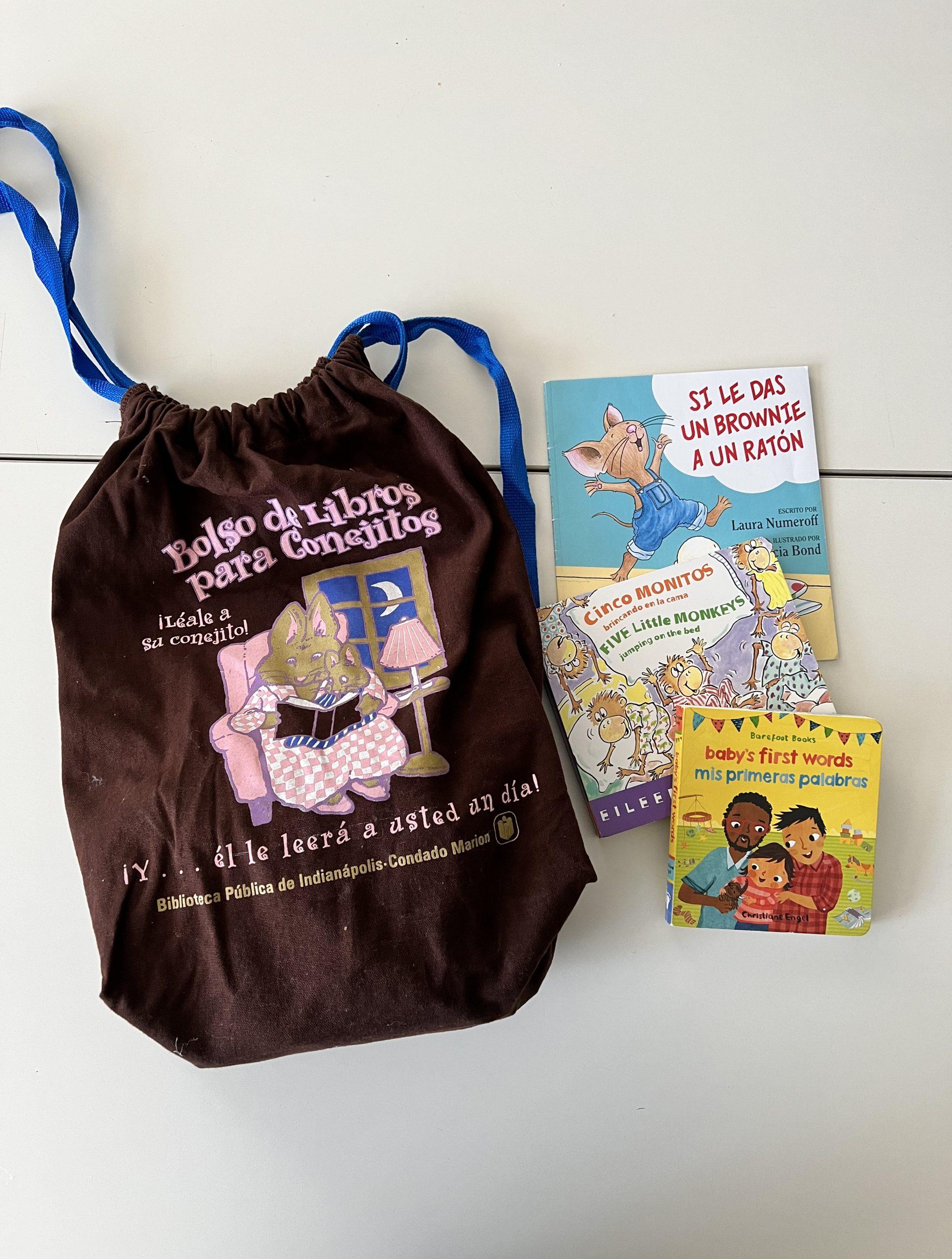 A brown bag with an illustration of a bunny reading. Several books are set up next to the bag.
