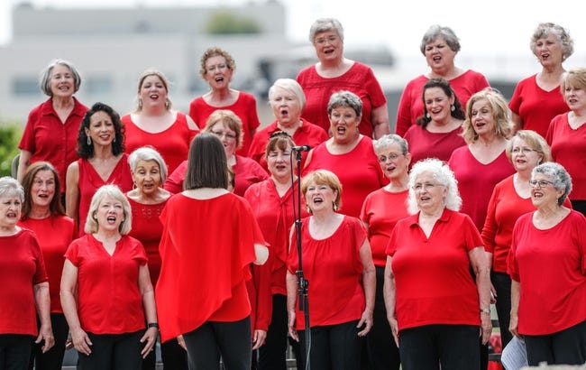 A group of women in red shirts are singing..