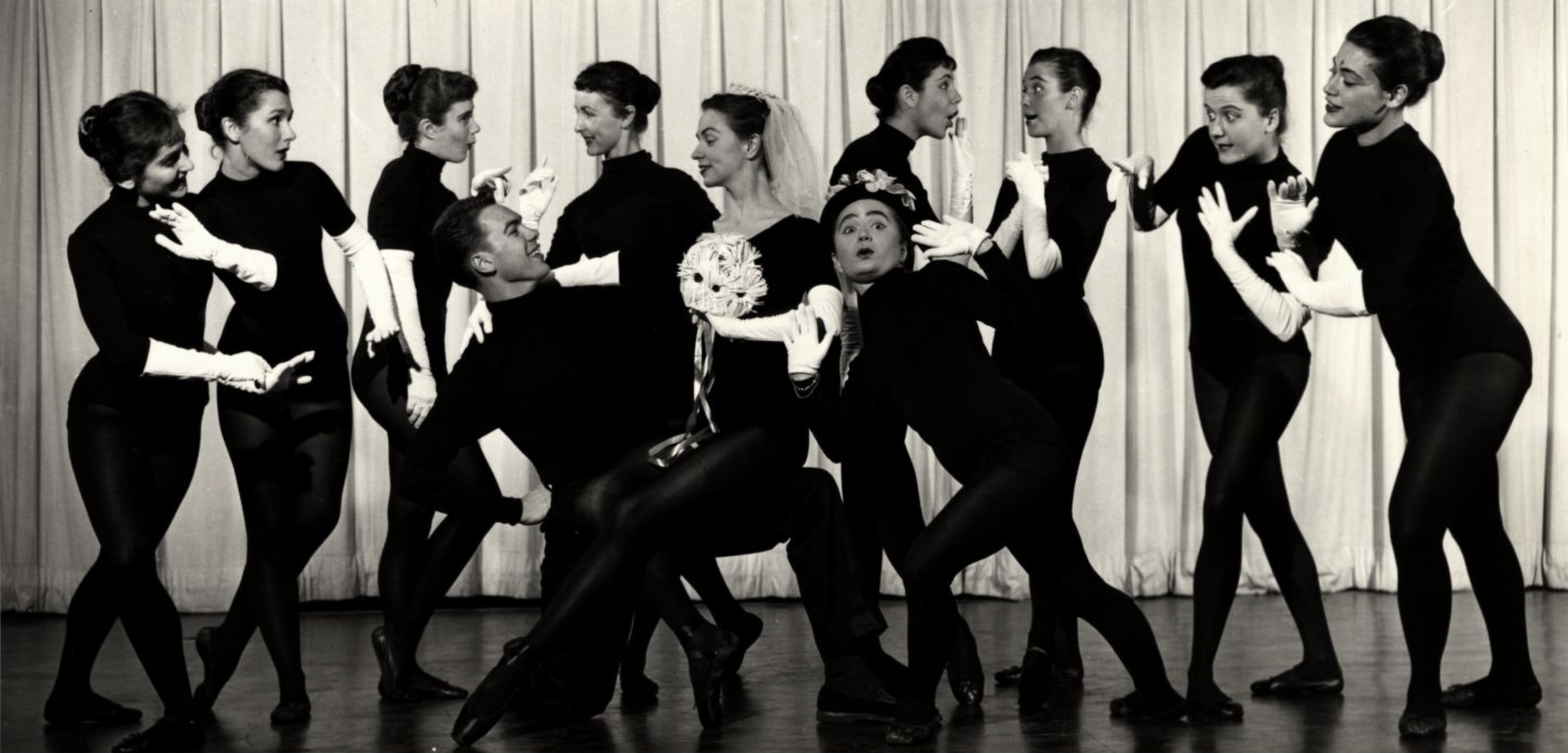 A group of dancers all wearing black clothing and white gloves.