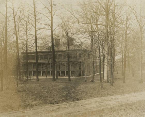 Sepia photo of a large, three-story house with twin chimneys.