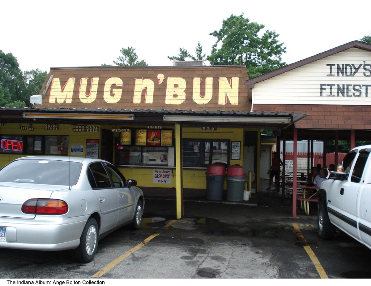 The one-story building says "Mug n' Bun across the front over a covered area where food orders are placed. To the right is a covered outdoor seating area.