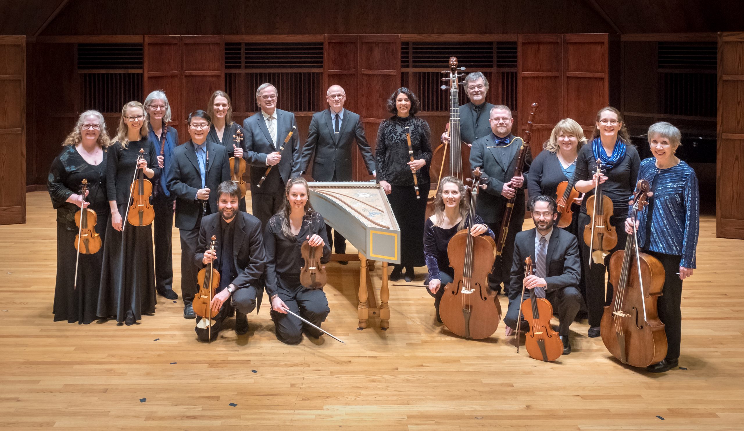 A group of musicians stand together, holding their instruments.