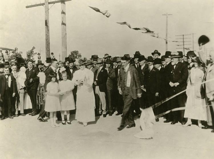 A crowd of people stand around a ribbon-cutting ceremony.