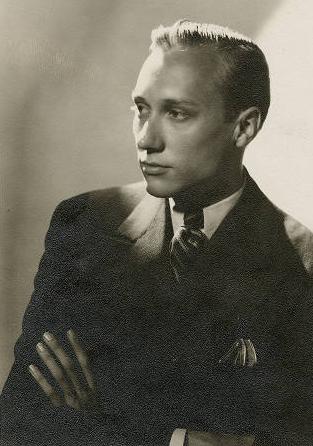 Stylish studio shot of a man with his arms folded. His head is illuminated and his body is in shadow.