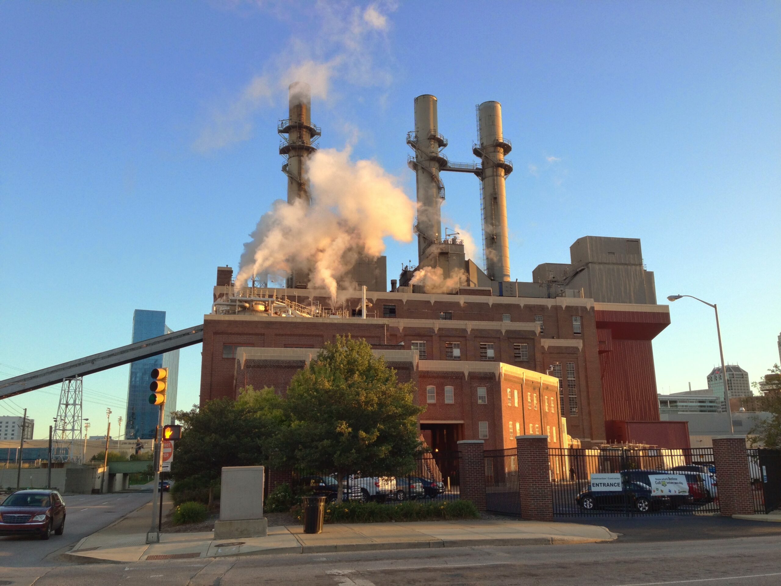 The building is a large, brick, industrial structure with three smokestacks on the roof.