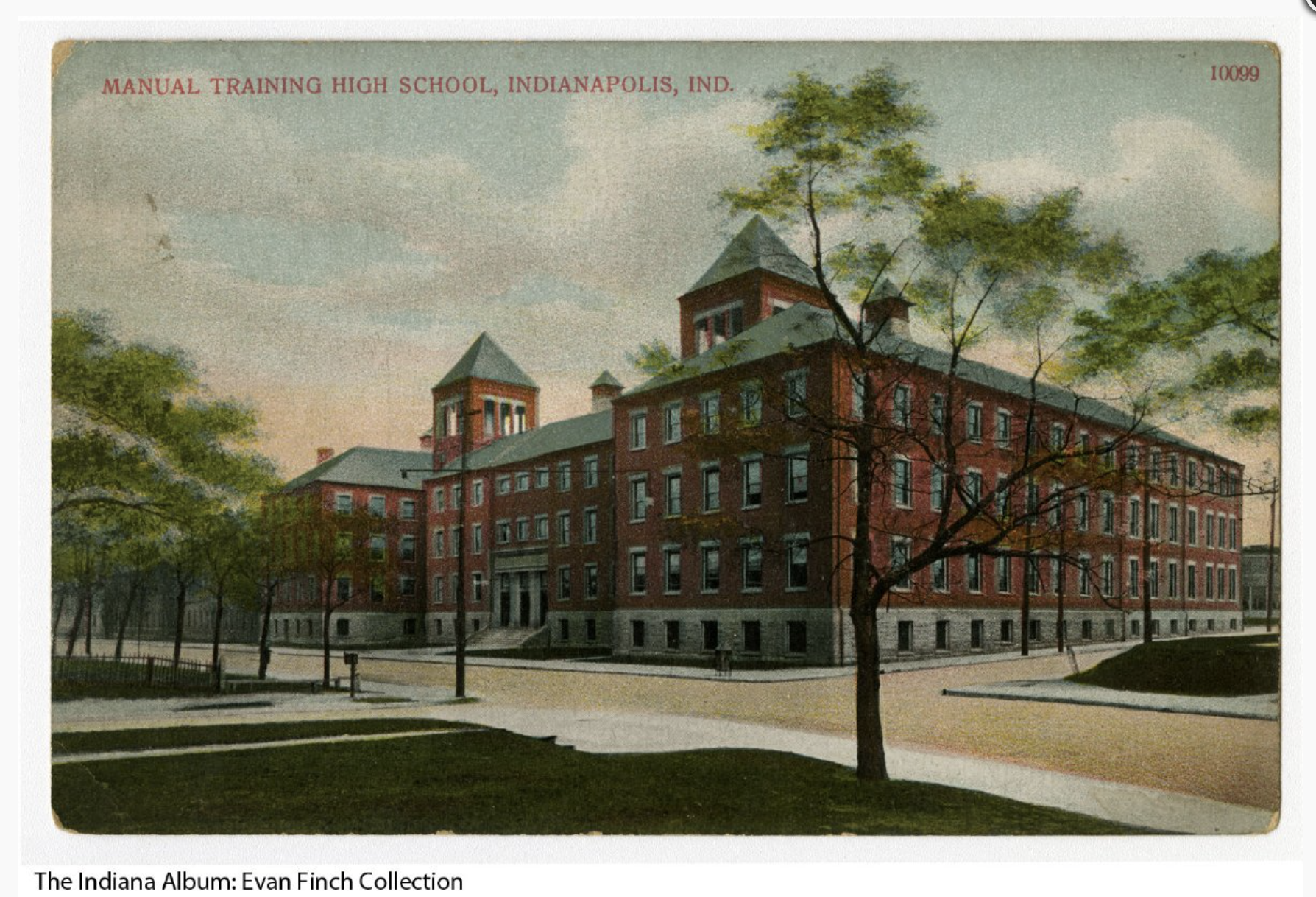 The school is a large four-story brick building with a limestone base and trim and two peaked towers on the roof.