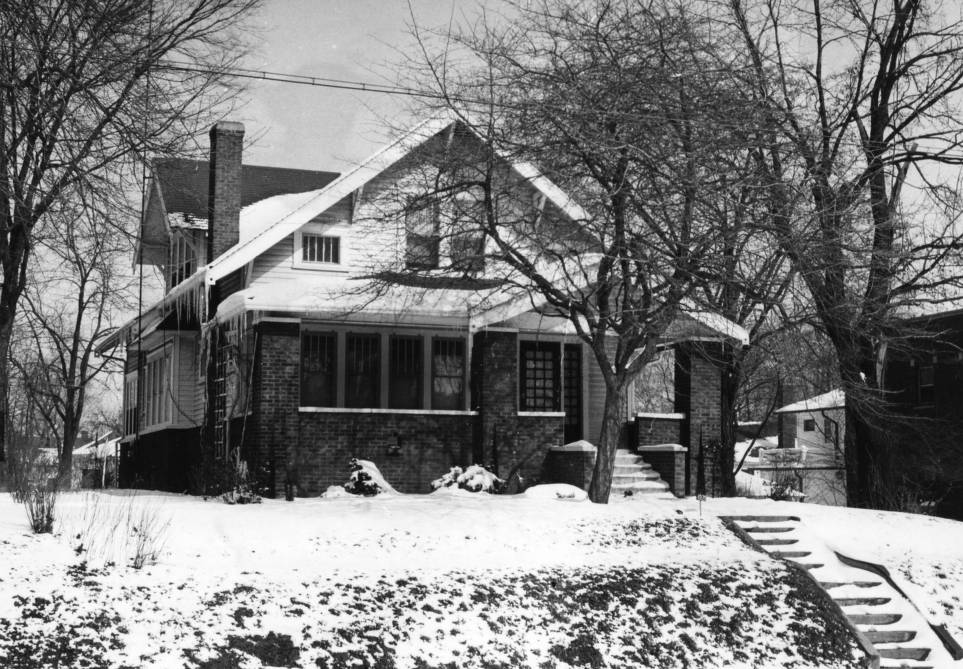 A residential house with a bricked front porch. Snow is on the lawn.